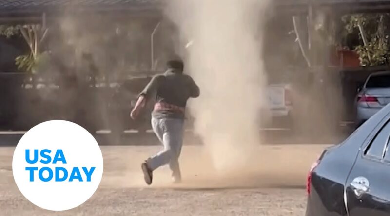 Man gleefully jumps through dust devil tornado at car park in Thailand | USA TODAY